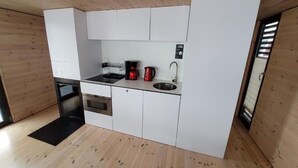 Ett kompakt kök med en inbyggd ugn, en diskho och en kaffebryggare.