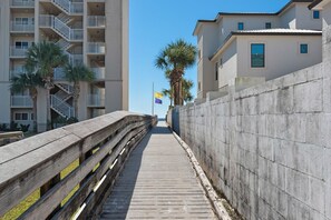 A wooden boardwalk leading to a building with a concrete wall and a flag.