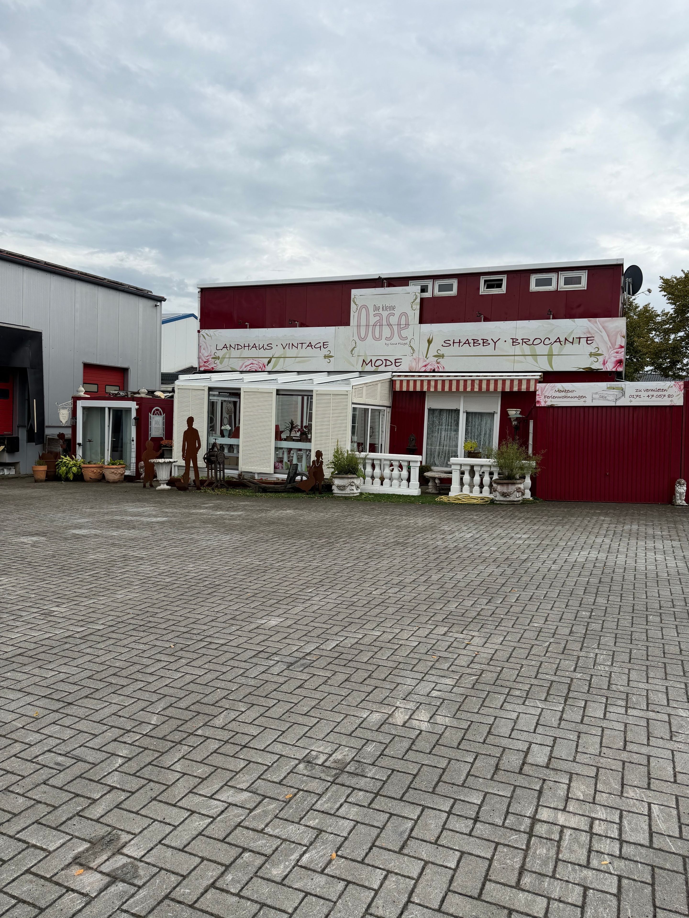 A storefront with a vintage sign, a red awning, and a paved entrance area.