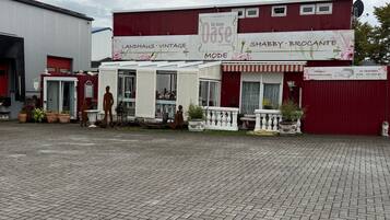 A storefront with a vintage sign, a red awning, and a paved entrance area.