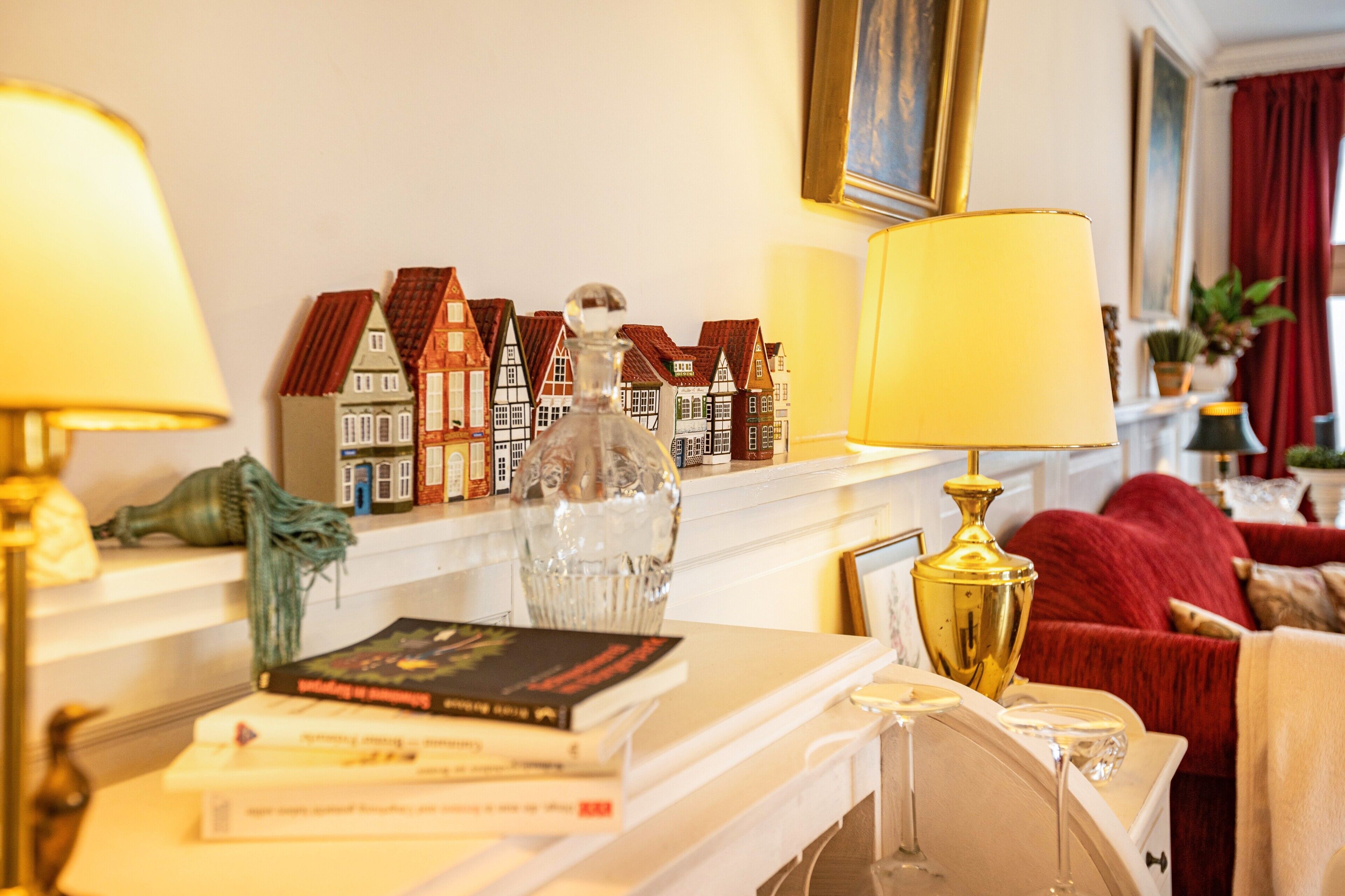 A room with a fireplace, books, decorative items, and a red sofa.
