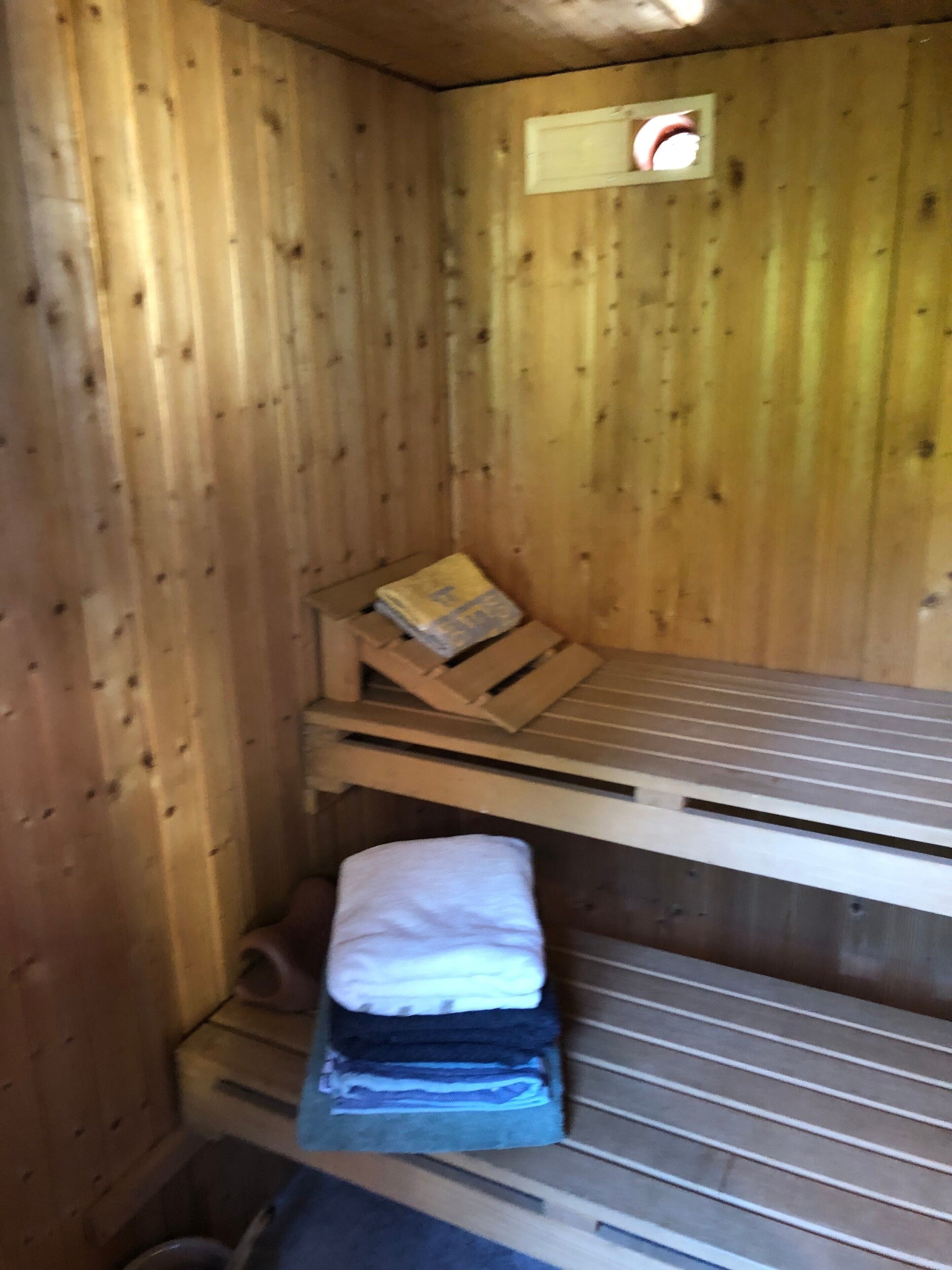 En stuga av trä med en våningssäng, ett litet fönster och en träbänk.