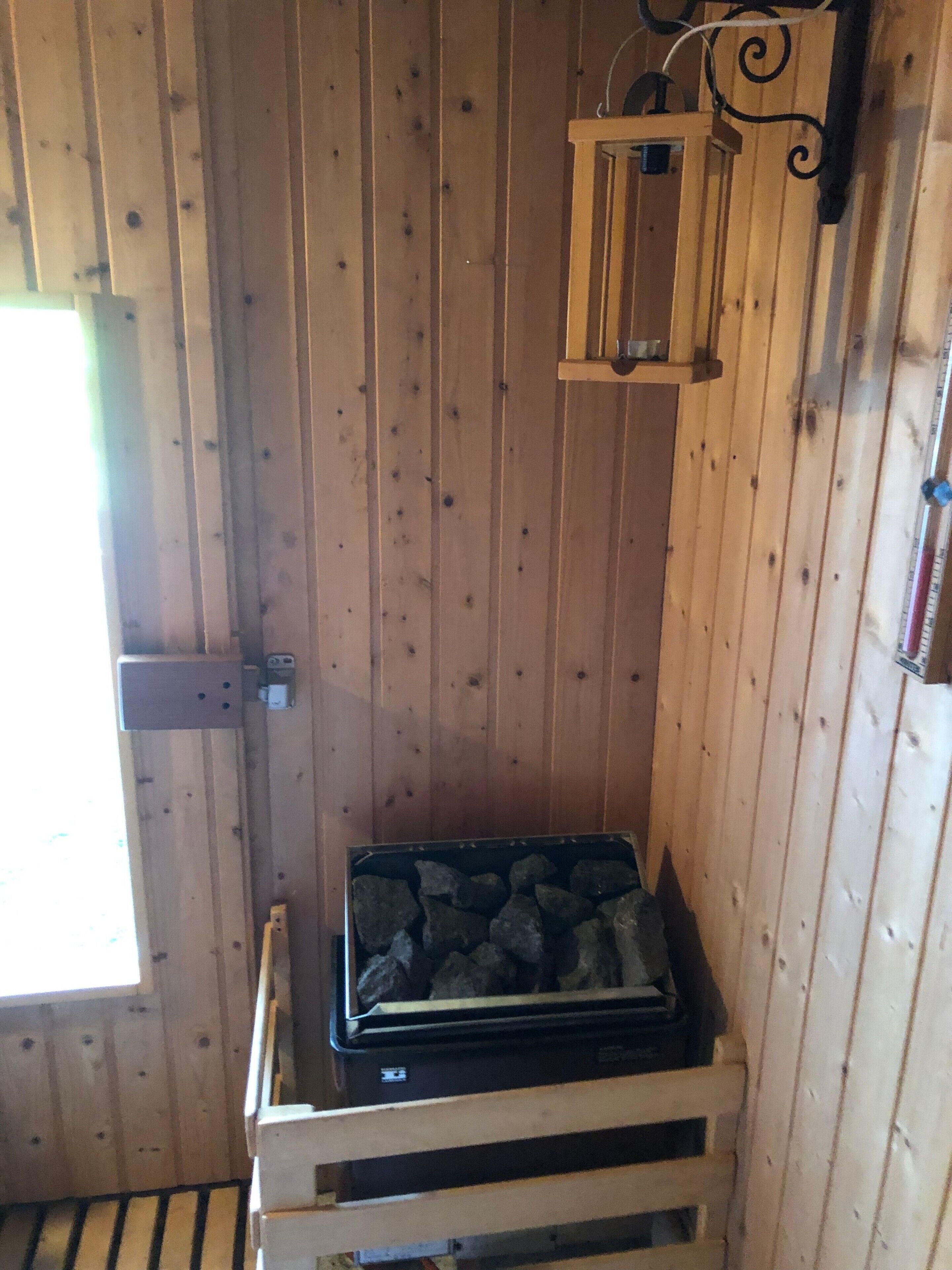 A wooden cabin interior with a stone fireplace, a window, and a hanging lantern.