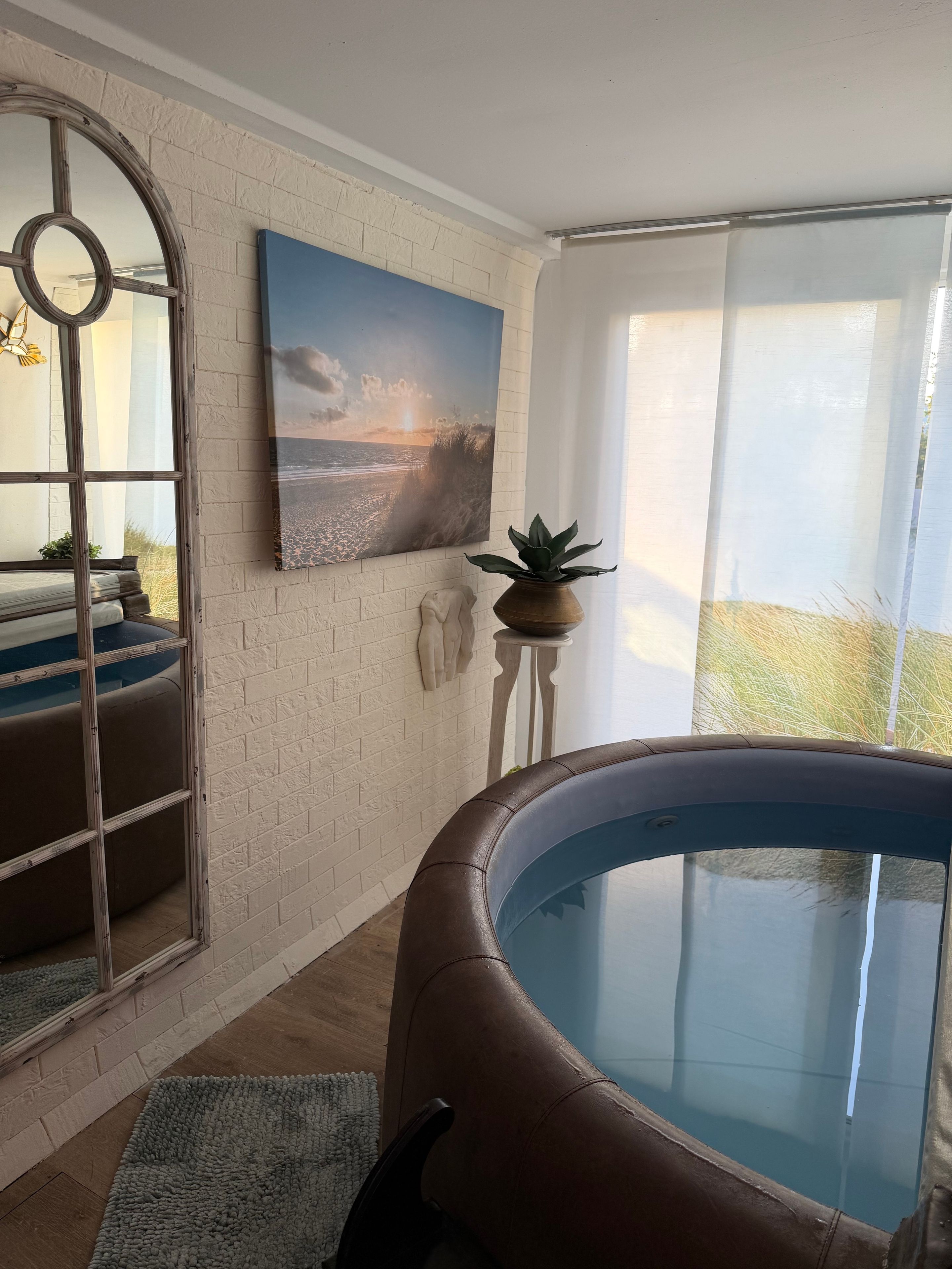 Ein Zimmer mit einem Pool mit Glasboden, einem großen Gemälde mit Strandmotiv und einer Backsteinwand.