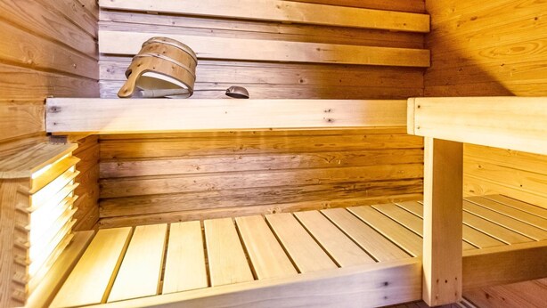 Una sauna de madera con bancos y un balde de metal.