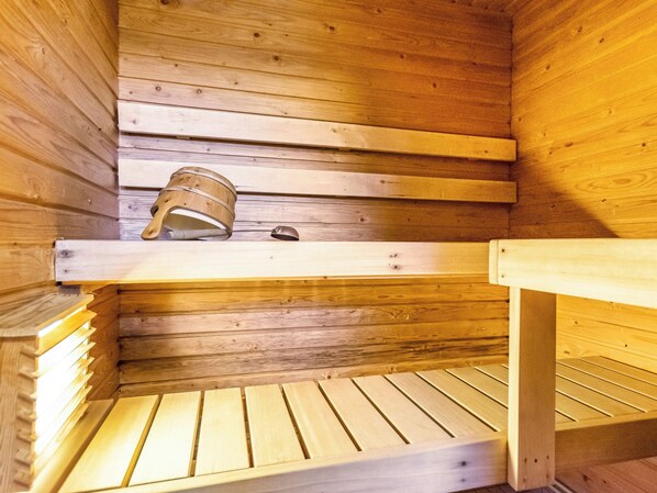 A sauna with wooden benches and a bucket.