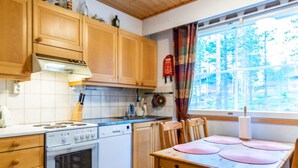 Una cocina con armarios de madera, una estufa y una mesa de comedor con sillas.