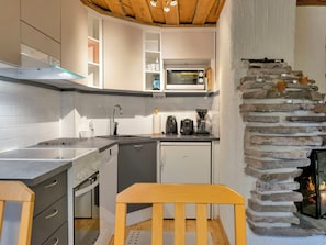 Cocina compacta con horno empotrado, microondas y chimenea de piedra.