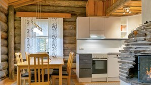 L’intérieur d’un chalet confortable, avec une salle à manger, une cuisine et une cheminée en pierre.
