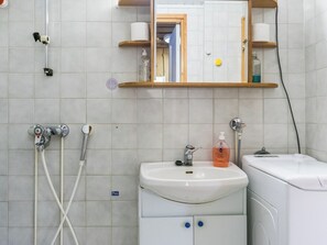 Ein Badezimmer mit einem weißen Waschbecken, einem Spiegel und einer Dusche.