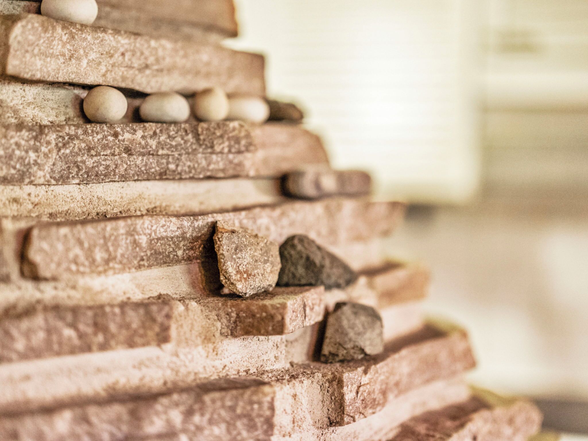A stack of bricks with some stones on top.