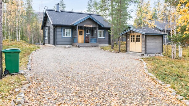 Eine Lodge mit Schotterauffahrt und einem kleinen Holzgebäude auf der rechten Seite.