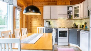 Eine moderne Küche mit Holzausstattung, einem Esstisch mit Stühlen und einer hängenden Pendelleuchte.