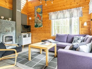 Een knus blokhutinterieur met een open haard, bank en televisie.