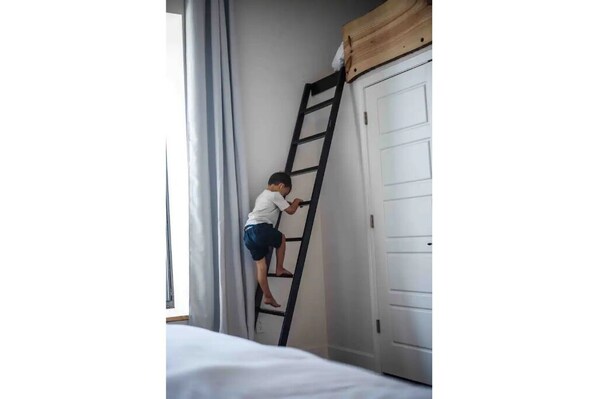 Un niño trepando una escalera hacia una puerta.