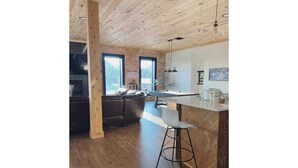 Eine moderne Küche mit Holzboden, einer Bar und großen Fenstern.