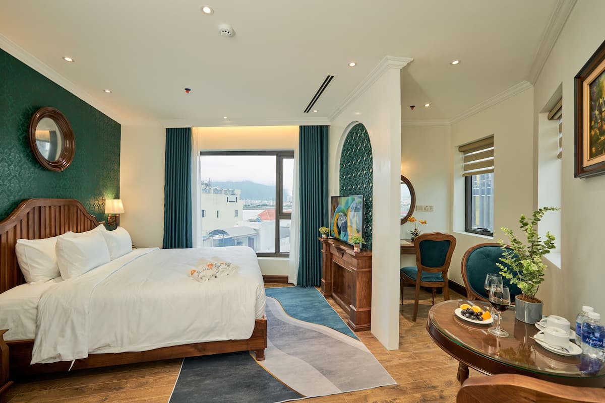 Une chambre d’hôtel avec un lit, une table à manger agrémentée d’un vase de fleurs, une chaise et une vue sur la ville.