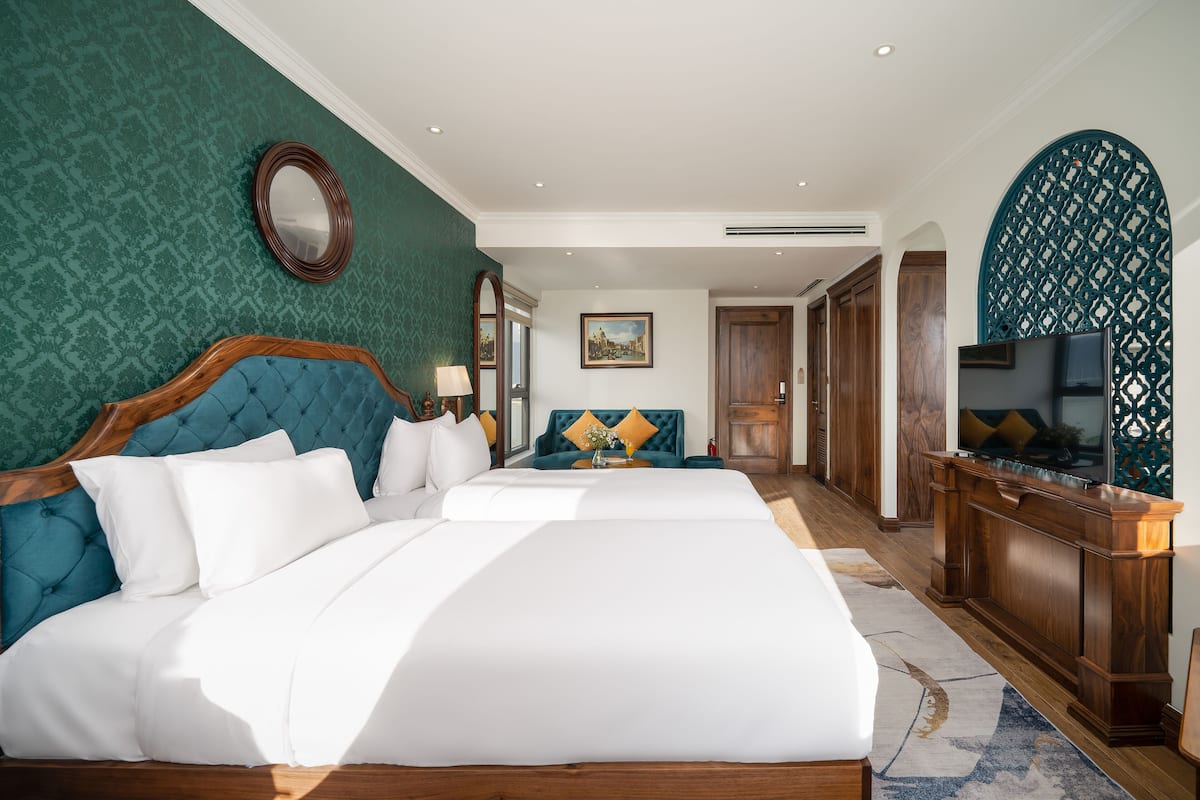 Une chambre d’hôtel avec un grand lit, un canapé, une télévision et un panneau décoratif au mur.