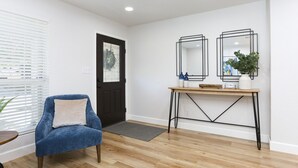 A modern living room with a blue armchair, a wooden coffee table, and a black-framed mirror. - Champions Getaway (San Antonio)