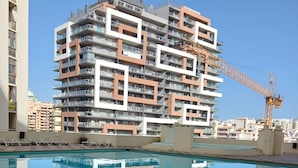 A modern building with multiple balconies and a construction crane in the background. - Varandas da Rocha 7 (Portimão)