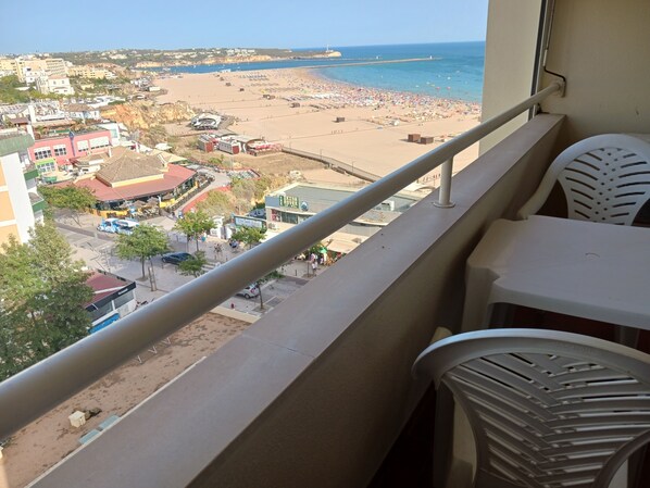 A balcony with a view of a beach, a parking area, and buildings in the background. - Varandas da Rocha 7 (Portimão)