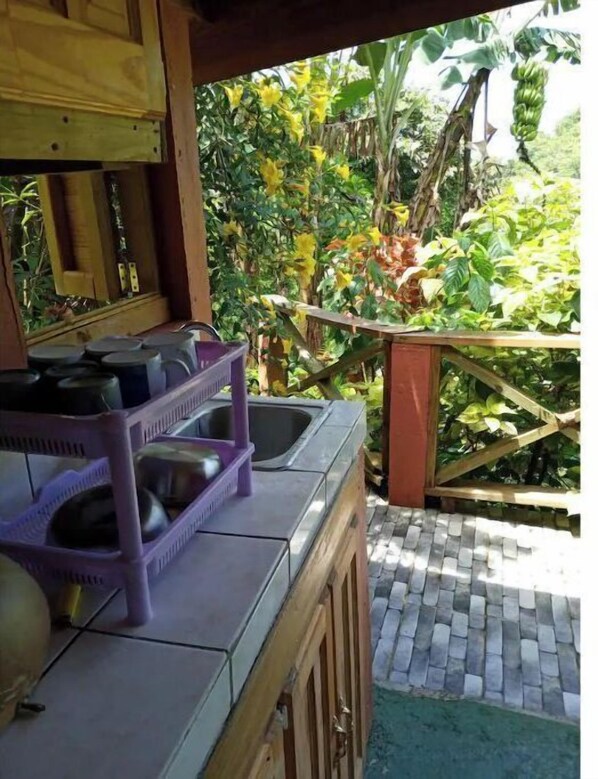 A kitchen area with a sink, a purple dish rack, and a tiled countertop.
