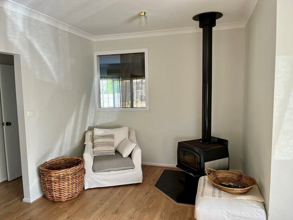 A cozy room with a white sofa, a black wood-burning stove, and wicker baskets.