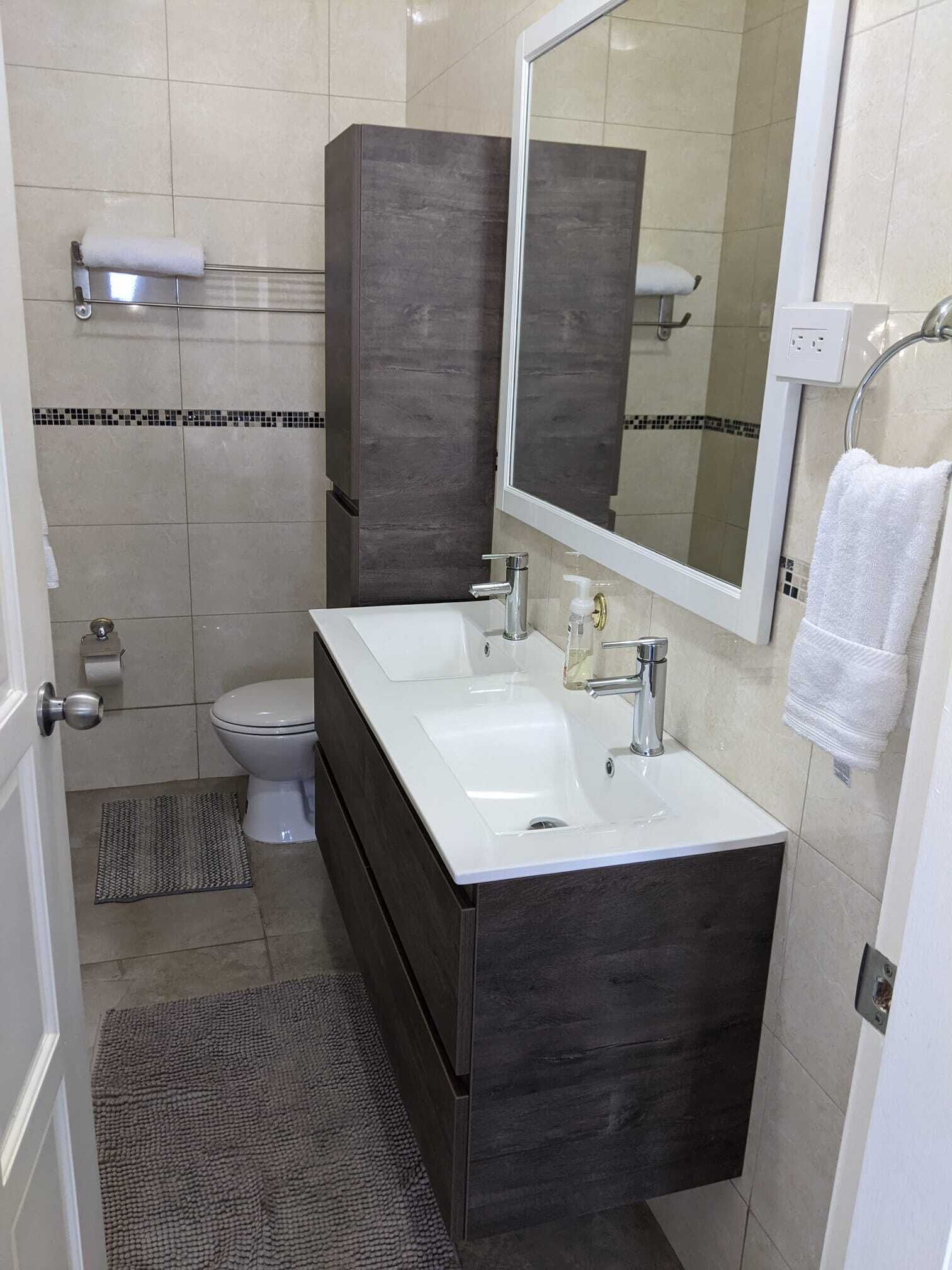 A modern bathroom with a white sink, dark wood vanity, and a large mirror.
