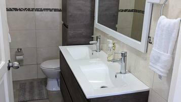A modern bathroom with a white sink, dark wood vanity, and a large mirror.