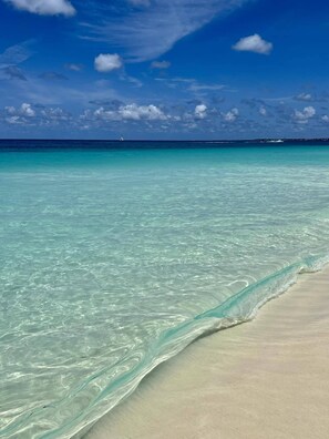 A beach with clear turquoise water and a sandy shore.