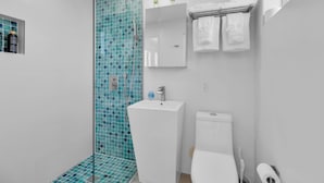 A modern bathroom with a glass shower enclosure, a white sink, a toilet, and a towel rack with folded towels. - 3. Waterfront Key Largo Studio | Scuba & Dock (Key Largo)