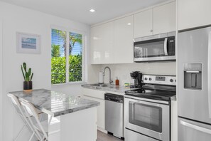 A modern kitchen with white cabinets, a stainless steel refrigerator, a microwave, an oven, and a dishwasher. - 3. Waterfront Key Largo Studio | Scuba & Dock (Key Largo)