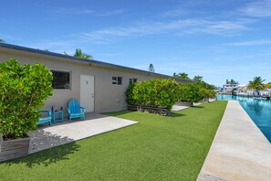A poolside area with a building, a lawn, and a clear sky. - 3. Waterfront Key Largo Studio | Scuba & Dock (Key Largo)