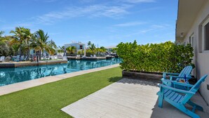 A pool area with artificial grass, a lounge chair, and a small building in the background. - 3. Waterfront Key Largo Studio | Scuba & Dock (Key Largo)