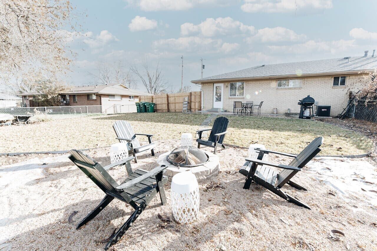 A backyard with a fire pit, outdoor seating, and a house in the background.