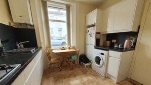 Una cocina compacta con una mesa de comedor, lavadora y ventana.