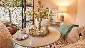 A cozy seating area with a table, a potted plant, a lamp, and a framed picture.