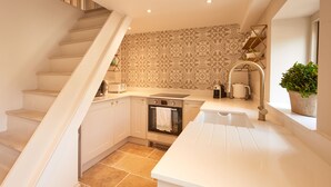 A modern kitchen with white cabinetry, a built-in oven, and a countertop with a sink.