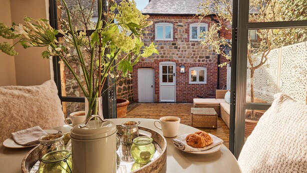 A cozy breakfast setting with a tray of tea, pastries, and a vase of flowers.