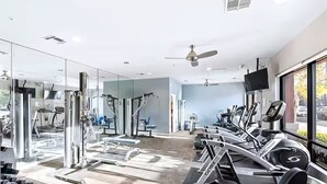 Een moderne sportschool met cardioapparatuur, gewichthefapparatuur en een grote spiegel.