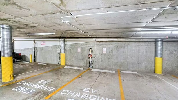 Een ondergrondse parkeergarage met laadpunten voor elektrische voertuigen, aangegeven op de vloer.