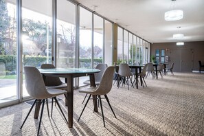 Conference room with a large, round table and six chairs, offering a view of the outdoors.