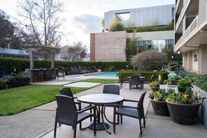 Relax and socialize in our outdoor space, featuring a pool, lounge chairs, and dining area surrounded by lush greenery.