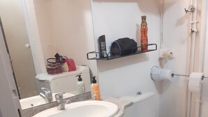 A bathroom with a white sink, a toilet, and a shelf with toiletries. - Pleasant T1 hyper center Valras plage (Valras-Plage)