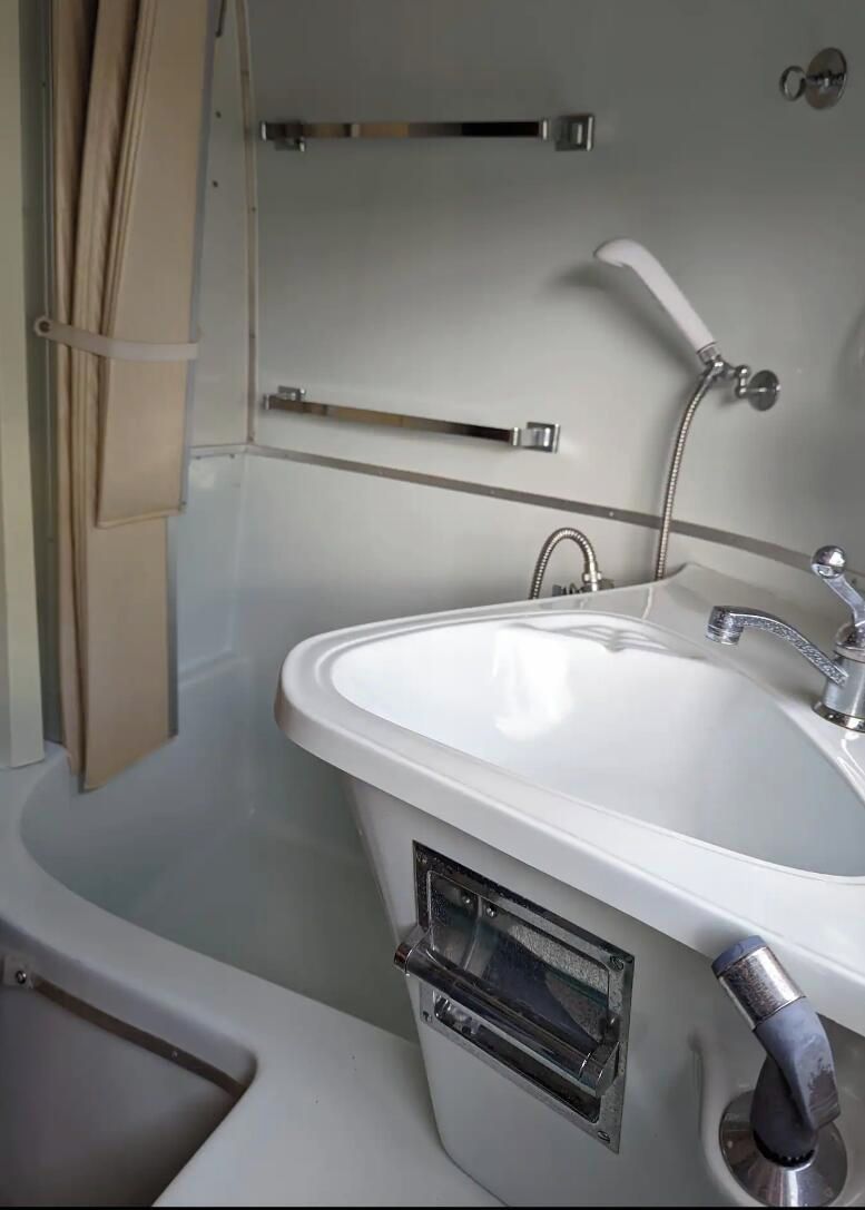 Een badkamer met een wit wastafelmeubel, een handdouche en een handdoekhouder.