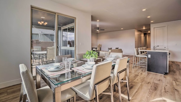 Een moderne eetruimte met een glazen tafel, metalen stoelen en een kroonluchter.