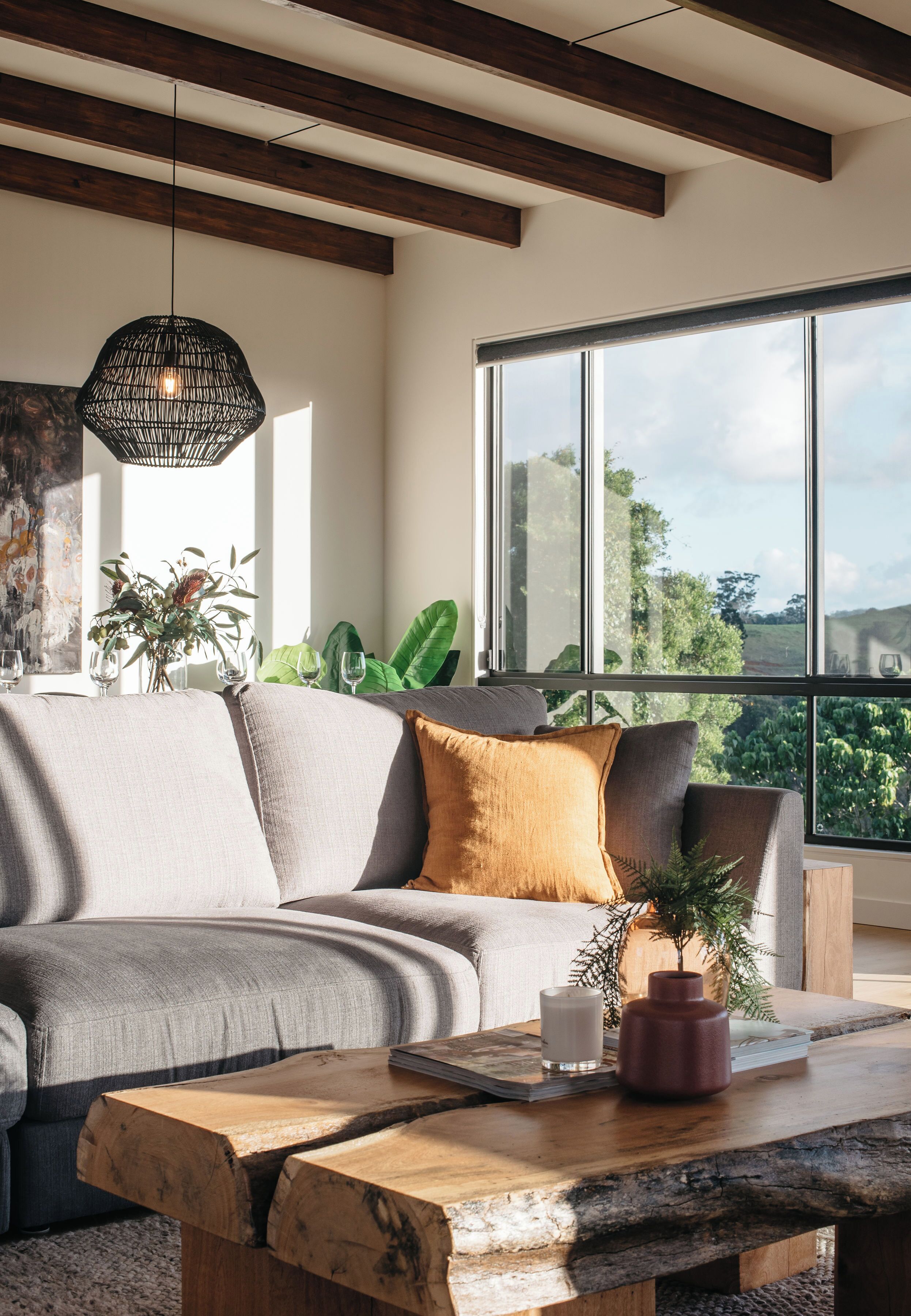 A modern living room with a sofa, a coffee table, and a large window with a view.