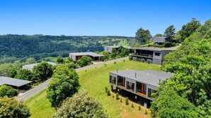 A modern residential complex with multiple houses, surrounded by lush greenery and hills. - The Ridge at Maleny (Booroobin)