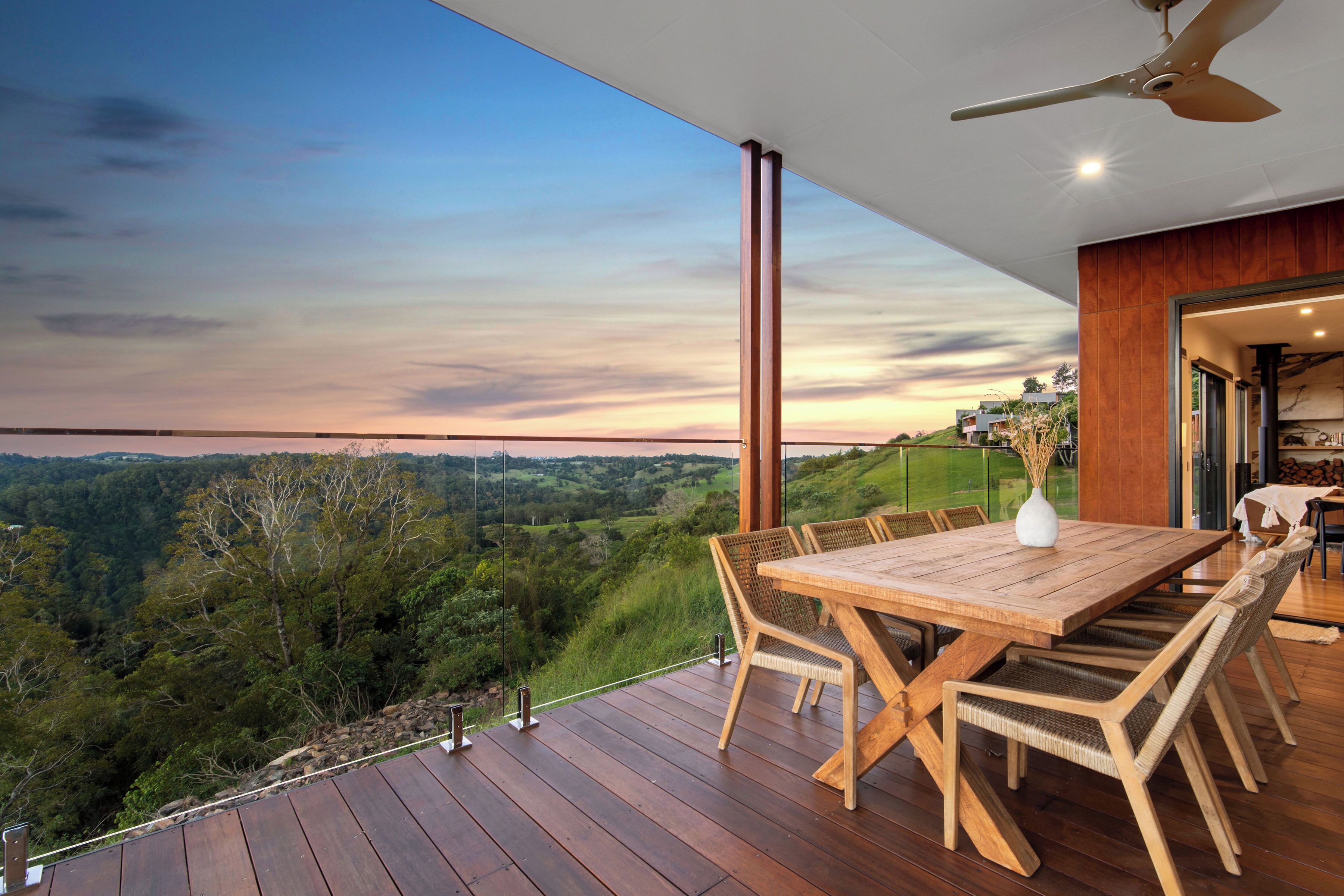 A wooden deck with a table and chairs, overlooking a scenic landscape.