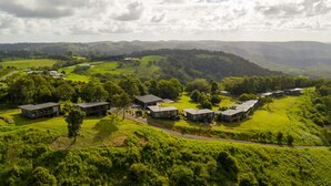 A modern residential area with multiple houses, surrounded by lush green hills and a winding road.
